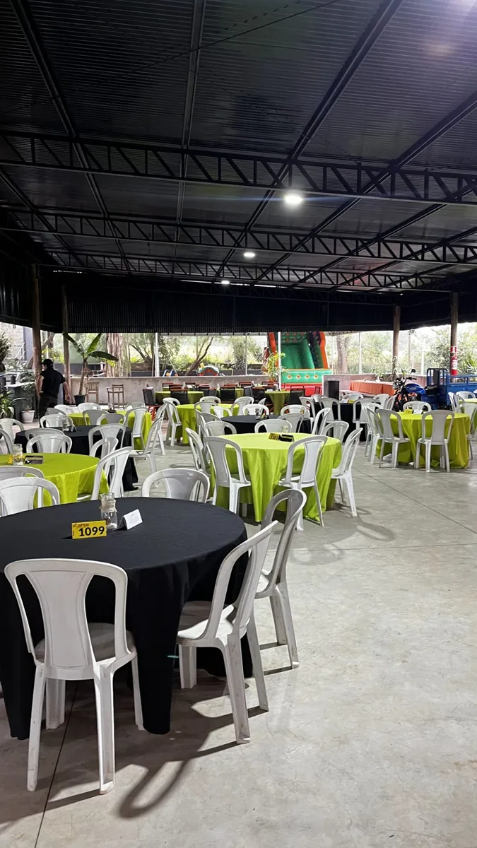 Salão coberto com mesas de toalha e brinquedo ao fundo